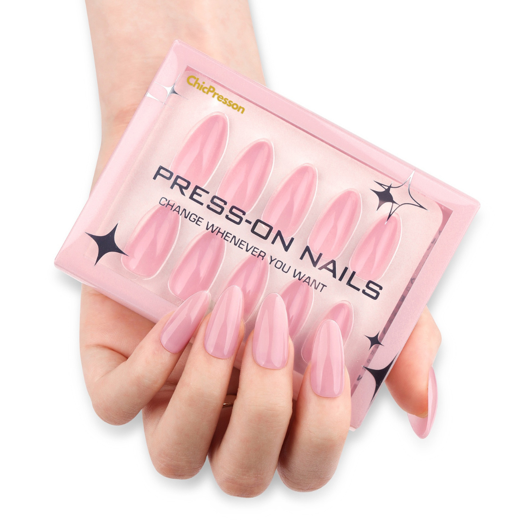 Pink press-on nails with a packaging box held by a hand on a white background