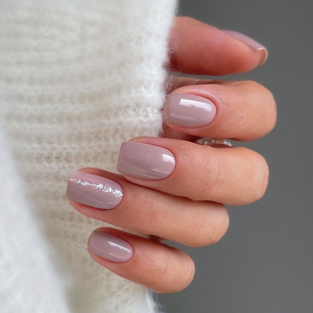 Close-up of a hand with light pink nail polish on a neutral background