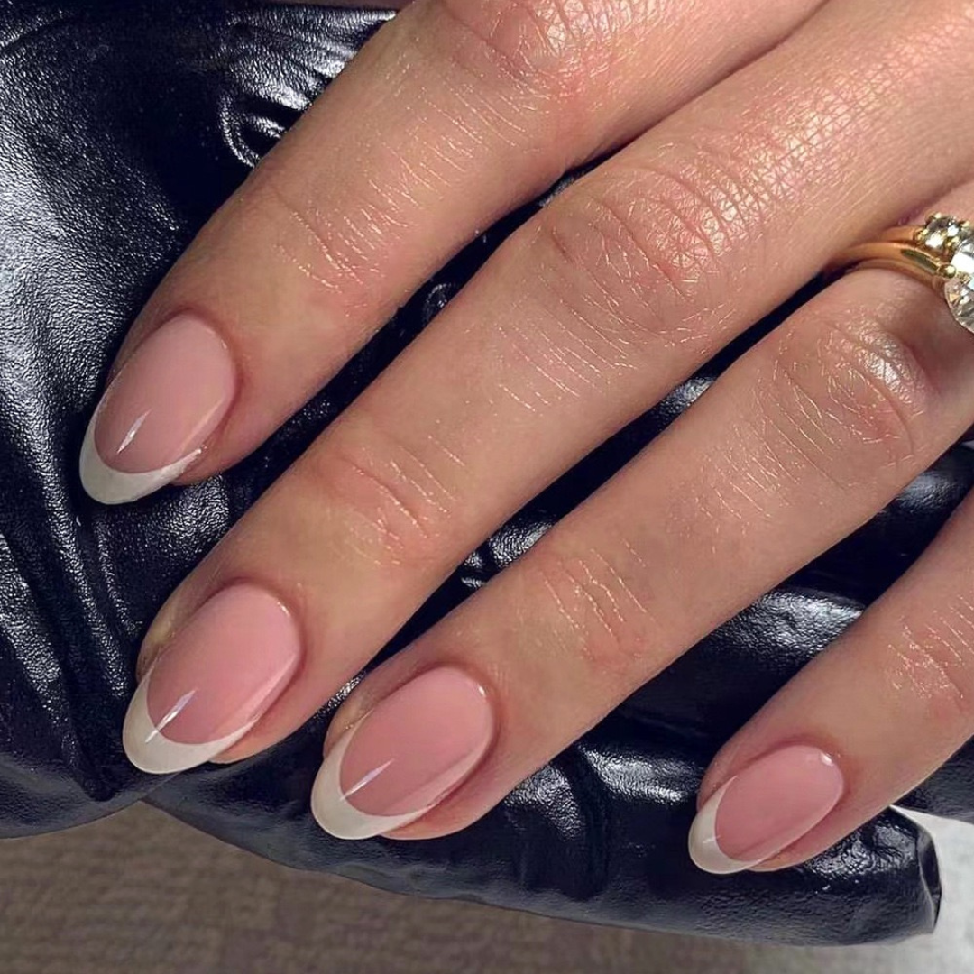 Close-up of a hand with pink and white nail polish on a dark textured background