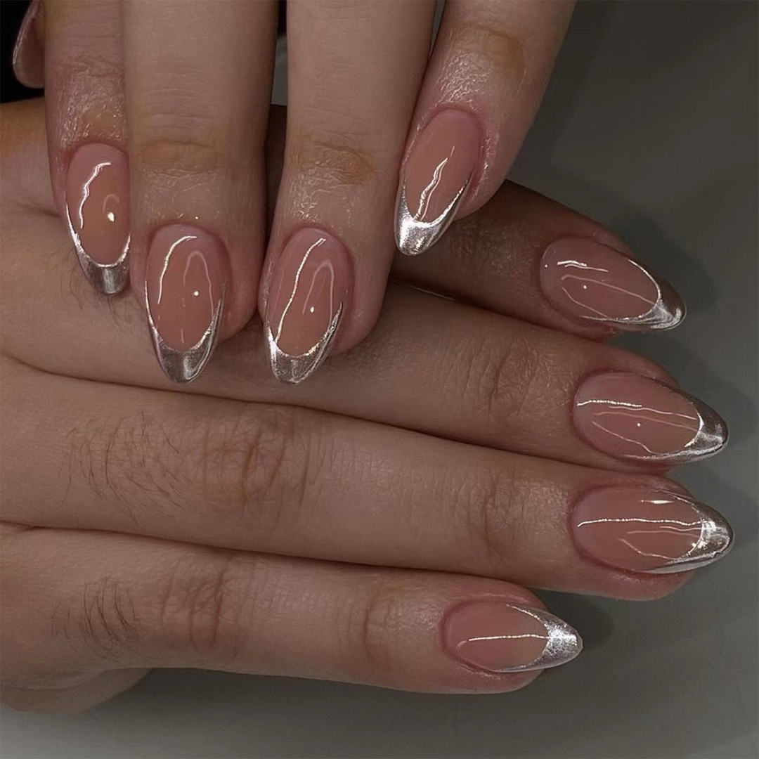Close-up of hands with almond-shaped nails featuring a metallic accent on a neutral background