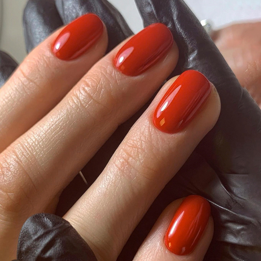 Close-up of a hand with red nail polish wearing a dark leather glove.