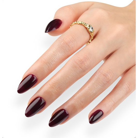 Hand with burgundy nail polish and a gold ring on a white background